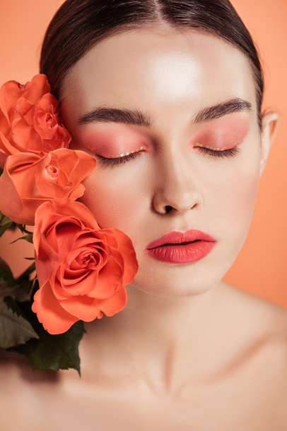 beautiful stylish girl posing with rose flowers isolated on coral - 写真・画像