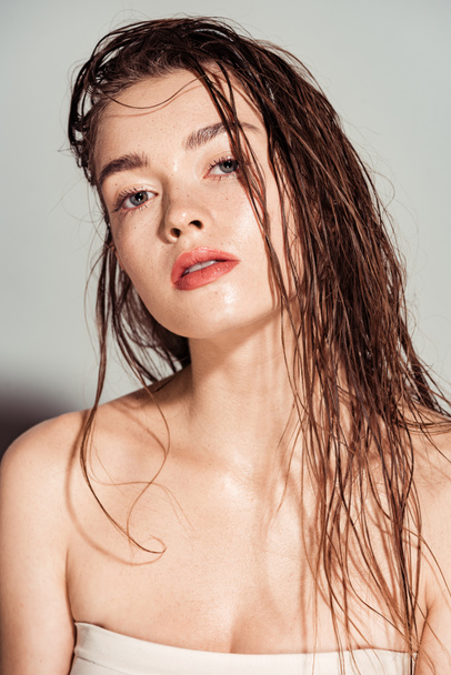 beautiful young woman with coral lips and wet hair looking at camera on grey background - Zdjęcie, obraz