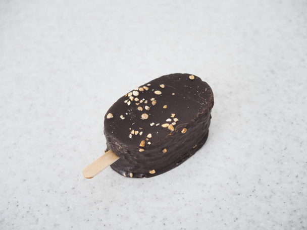 délicieux eskimo de crème glacée sur un bâton recouvert de chocolat repose sur une table en marbre
 - Photo, image
