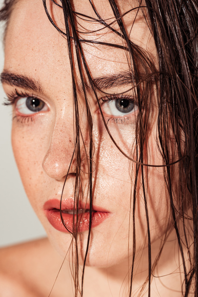 retrato de menina bonita com lábios de coral e cabelos molhados olhando para câmera isolada em cinza
 - Foto, Imagem