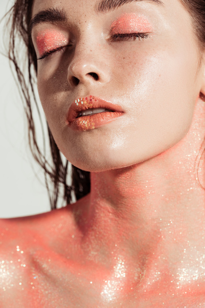 bela menina elegante com maquiagem de brilho de coral e olhos fechados isolados em cinza
 - Foto, Imagem