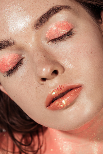 close up of beautiful girl with coral glitter makeup and eyes closed - 写真・画像