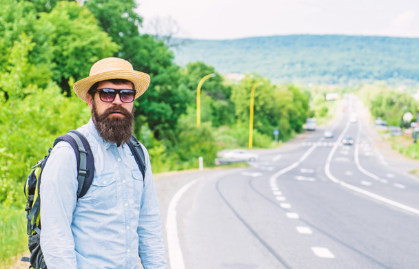Man at edge of highway looking for transport. On the road. Hitchhiking means transportation that gained asking strangers for ride in their car. Hitchhiker try to stop transport to get to destination - 写真・画像