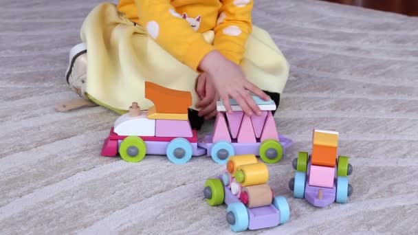 Маленькая девочка играет с обучающим игрушечным поездом, сидя на полу дома
 . - Кадры, видео