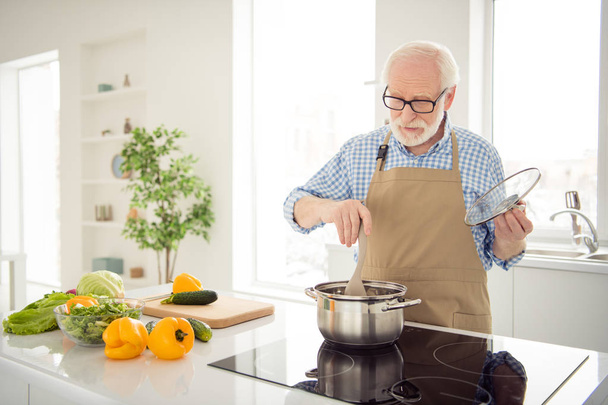 Close up photo grey haired he his him nonno waiting guests cooking favorite family dish trying mixing process wait ready wear specs casual checkered plaid shirt jeans denim outfit modern kitchen
 - Foto, immagini