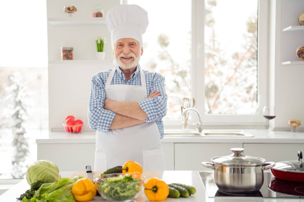 Close up photo grey haired he his him grandpa arms crossed excited glad overjoyed self-confident wear baker chefs costume casual checkered plaid shirt jeans denim outfit modern kitchen - Foto, Imagen