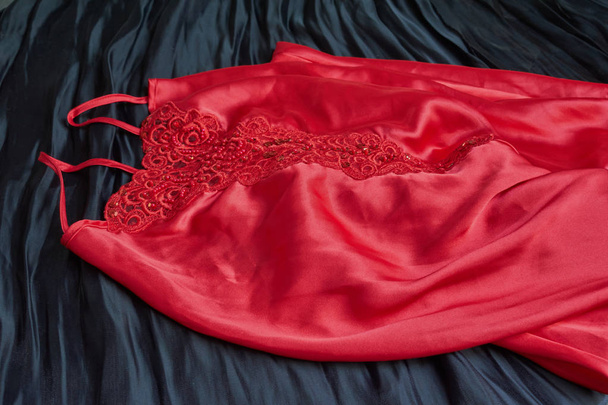 Жіноча червона атласна нічна сукня ізольована на чорному тлі
 - Фото, зображення