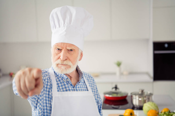 Close up photo grey haired he his him grandpa arm hand finger it is your fault my dish spoiled rage face wear baker chefs costume casual checkered plaid shirt jeans denim outfit kitchen - Фото, изображение