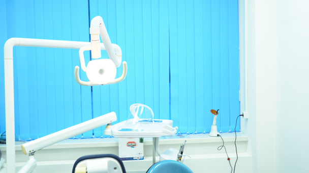 Fotel dentystyczny i inne akcesoria używane przez dentystów w niebieski, Medyk światła, koncepcja medycyna. Nowoczesny sprzęt dentystyczny w pustej szafy. - Zdjęcie, obraz