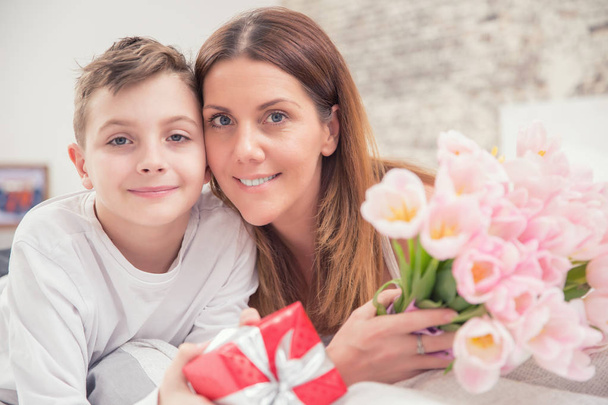 Happy mother's day concept. Mom with son on bed with gift and tu - Zdjęcie, obraz