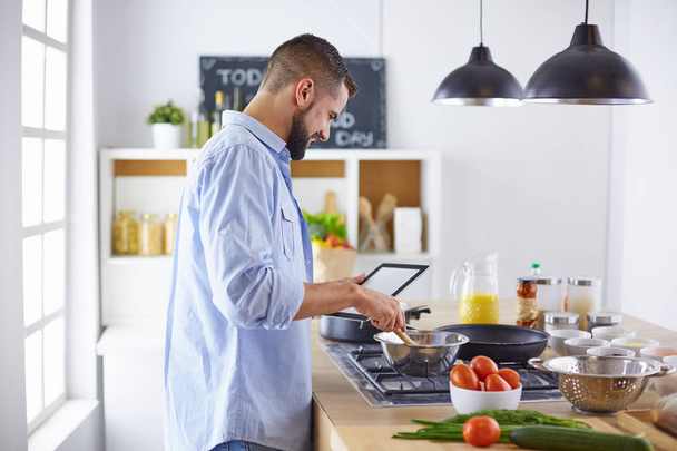 Улыбающийся и уверенный шеф-повар стоит на большой кухне - Фото, изображение