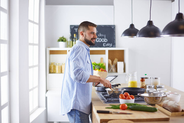 Усміхнений і впевнений шеф-кухар стоїть на великій кухні
 - Фото, зображення