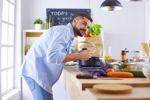 Lachende en vol vertrouwen chef-kok permanent in een grote keuken proeven een gekookte schotel - Foto, afbeelding