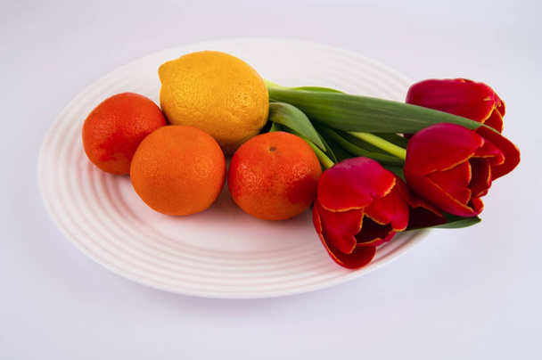 citrus fruits and tulips on a white plate - Fotó, kép