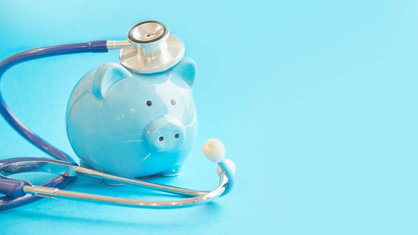 Piggy bank with stethoscope isolated on blue background. concept of financial literacy. Creating and maintaining a budget. keeping their finances on track. ruin loan history - Фото, зображення