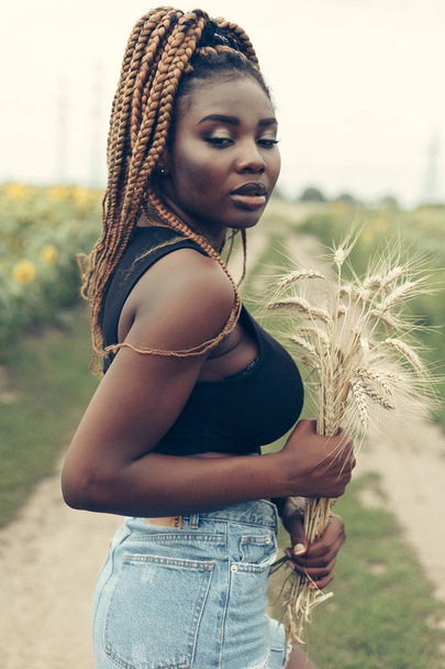 African American girl in a field of yellow flowers at sunset - Fotoğraf, Görsel