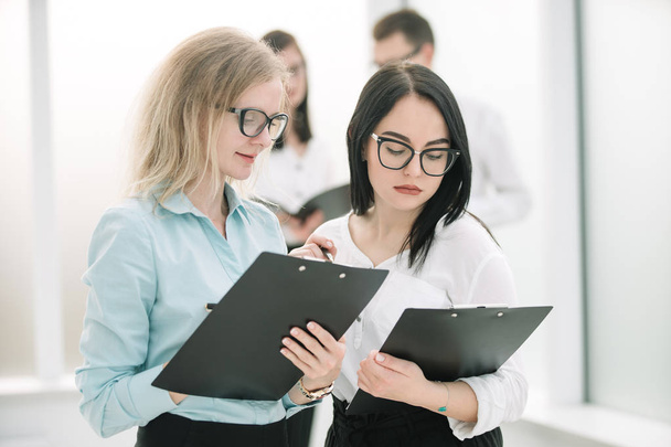 two business women discussing business documents standing in the office. - 写真・画像