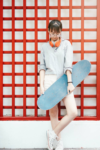 Joven hipster asiático chica sosteniendo monopatín
. - Foto, imagen