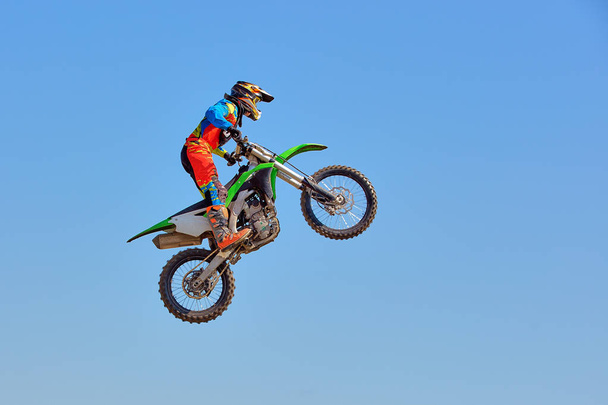 Fondo de deportes extremos - silueta de motociclista saltando en moto al atardecer, contra el cielo azul
 - Foto, Imagen