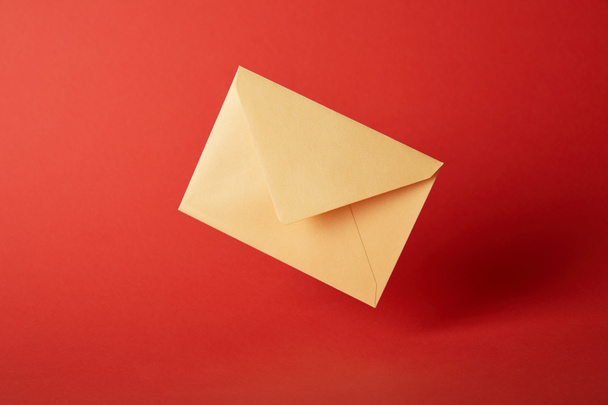 bright, colorful and yellow envelope on red background with copy space  - 写真・画像
