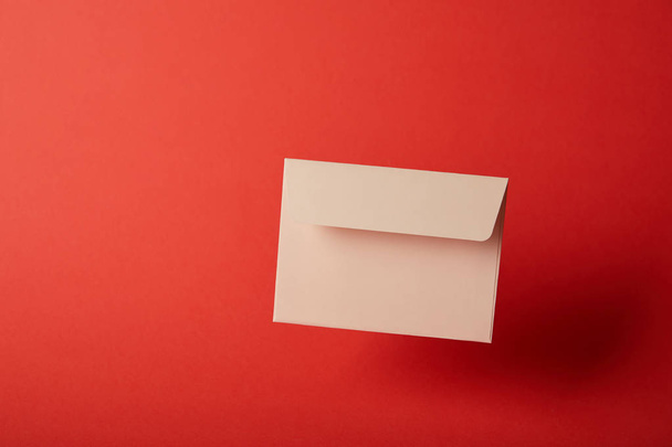 beige, blank and empty envelope on bright red background with copy space  - Foto, Bild