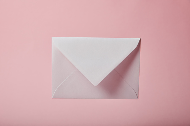 white and empty envelope on pink background with copy space - Foto, afbeelding