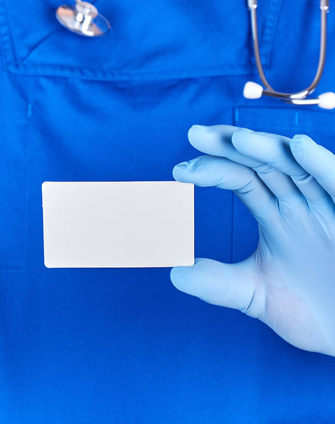 male doctor wearing blue latex gloves is holding a blank white p - Фото, зображення