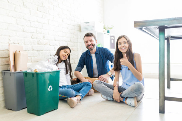 Preteen dziewczyna gestykulacji thumbs up siedząc przez ojca i siostry po zbieranie odpadów - Zdjęcie, obraz