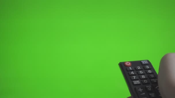 Male hand with remote control turns on the TV over green screen. Place for your advertisement. - Footage, Video