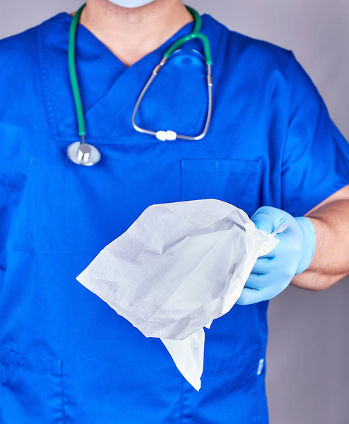 Doktor v modré jednotné a sterilní latexové rukavice drží bílá  - Fotografie, Obrázek