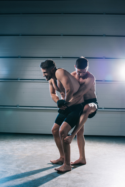 muskulöser MMA-Kämpfer, der einen sportlichen Gegner ohne Hemd besiegt  - Foto, Bild