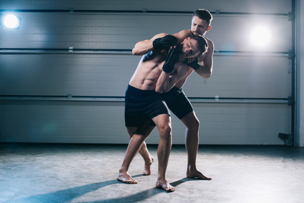 muscular mma fighter doing chokehold to sportive shirtless opponent  - Photo, Image
