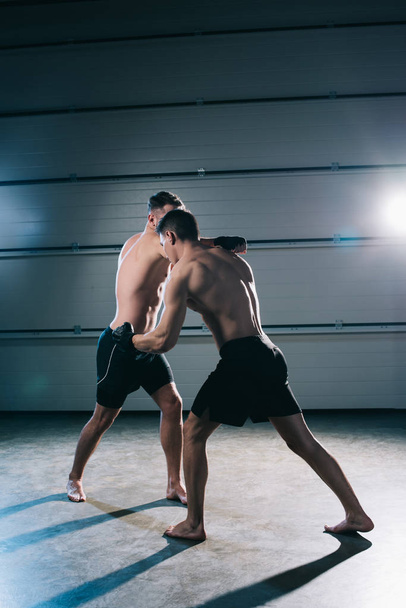 vahva paidaton mma urheilijat taistelevat kun mies lyömällä käsivarsi toinen
 - Valokuva, kuva
