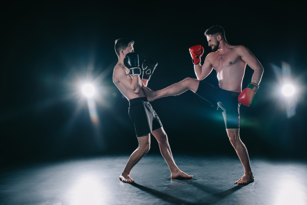 без сорочки м'язистий боєць в боксерських рукавичках штовхає іншого в торс
  - Фото, зображення