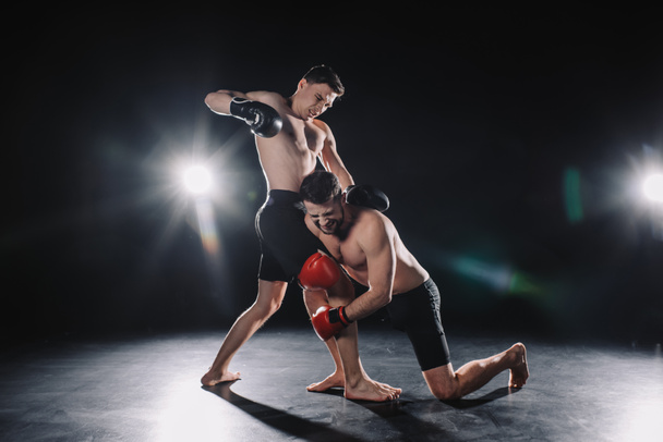 descalzo fuerte muscular mma luchador en guantes de boxeo asegurando otro mientras deportista golpeándolo
 - Foto, imagen