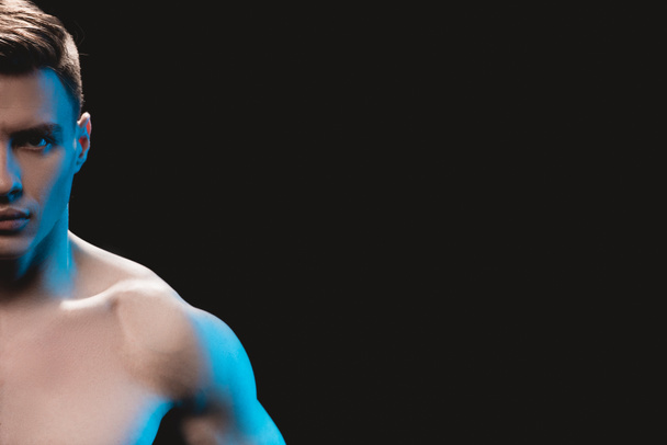 обрезанный вид красивого мускулистого спортсмена, смотрящего на камеру, изолированную на черном
 - Фото, изображение