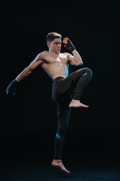 muscular sin camisa extenuante mma luchador en las vendas saltando aislado en negro
 - Foto, imagen