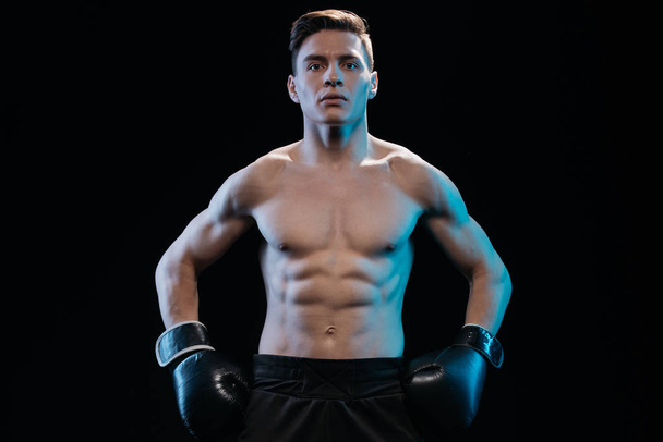 впевнений м'язистий спортивний боксер в боксерських рукавичках позує ізольовано на чорному
 - Фото, зображення