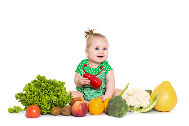 Baby girl sitting surrounded by fruits and vegetables, isolated  - Foto, imagen