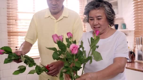 Asian elderly couple making bouquet flowers on a wooden table in kitchen at home. Chinese sweet senior couple using time relax together at home. Lifestyle senior couple at home concept.  - Video, Çekim