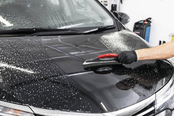 A man cleaning car with plastic sponge. Car detailing or valeting concept. Selective focus. Car detailing. Cleaning with sponge and cloth. Worker cleaning. Car wash concept solution to clean - Zdjęcie, obraz
