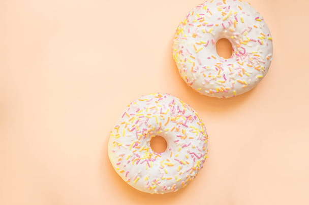 Donut with white icing colored topping, isolated on yellow background.Tasty classic two glazed donuts isolated.Delicious colorful donuts - Photo, image