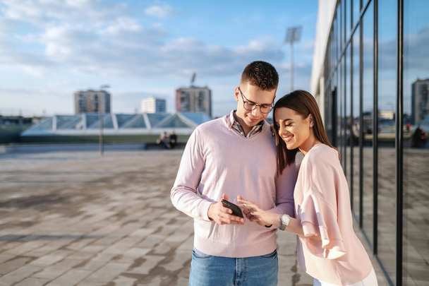 Jovem branco elegante casal em pé na varanda e olhando para o telefone inteligente
. - Foto, Imagem