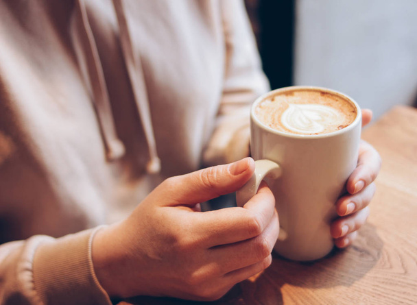 Чашка кофе капучино в женских руках в кафе, закрыть
 - Фото, изображение