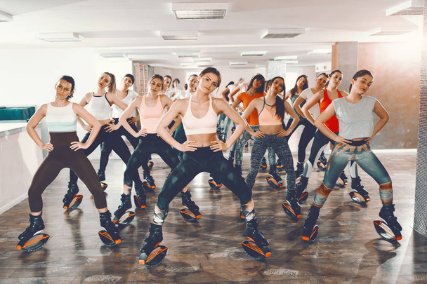 Group of girls with healthy habits doing exercises in kangoo jumps footwear. Gym interior. Control the mind, control the body. - Photo, Image