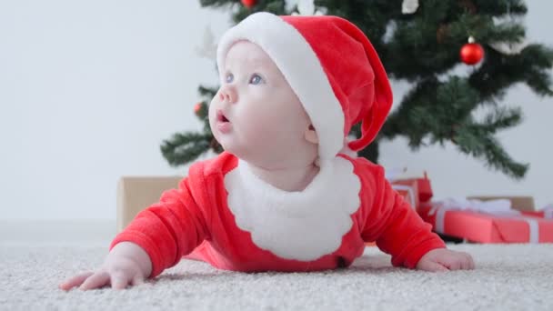 Schattige baby in het kostuum van de Kerstman, op zoek naar een geschenk - Video