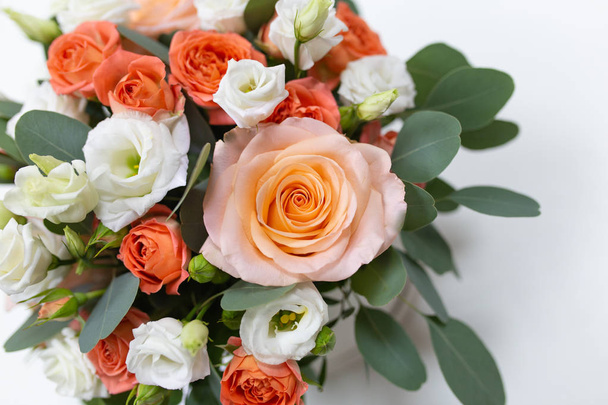 Delicate floral arrangement of roses (white, pink, orange) and green eucalyptus leaves in a round white cardboard box on a light background - Zdjęcie, obraz