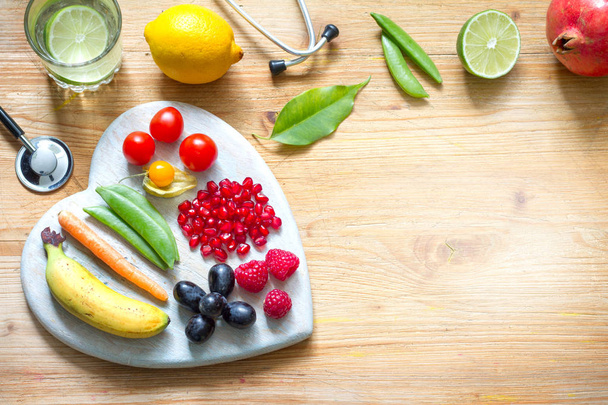 Vegetariánské jídlo v srdci a fonendoskop s vodou alternativní medicíny pozadí koncept zdravého životního stylu - Fotografie, Obrázek