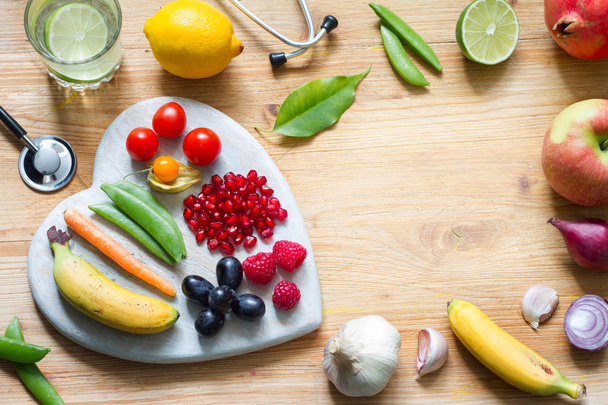 Gezonde levensstijl vegetarisch voedsel in hart en stethoscoop met water alternatieve geneeskunde achtergrond concept - Foto, afbeelding
