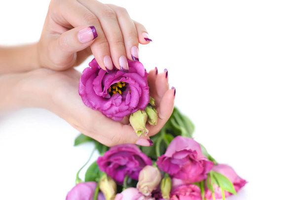 Hände einer Frau mit rosa Maniküre und Blumen Eustoma - Foto, Bild